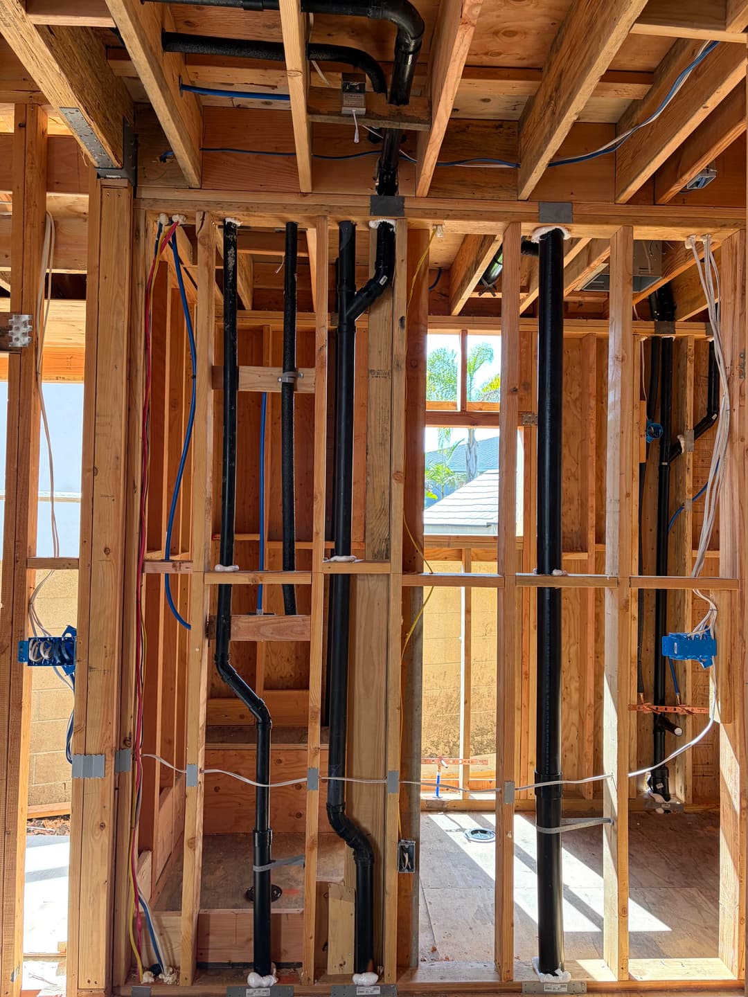 Framing and plumbing installation in a residential construction project with exposed pipes.