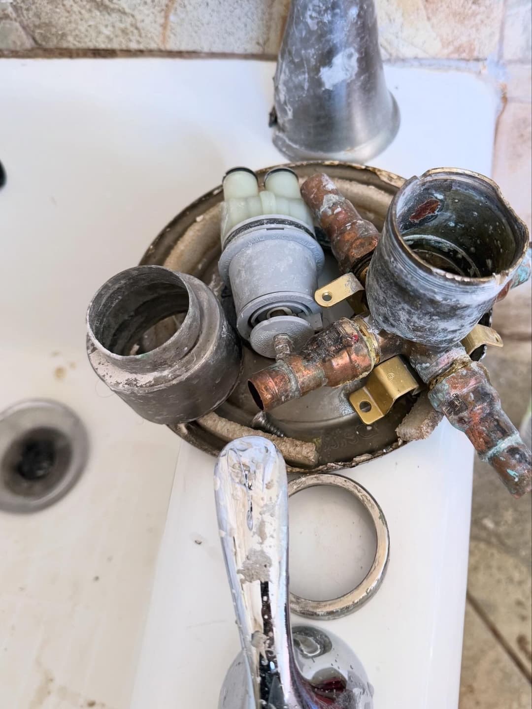 Disassembled bathroom faucet components on a sink, showing pipes and hardware details.