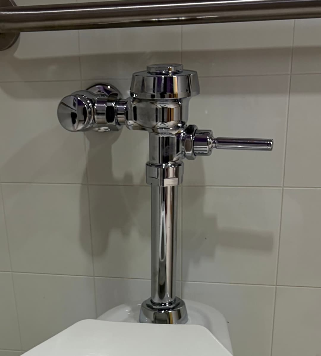 Chrome toilet flush valve installation in a modern restroom setting.
