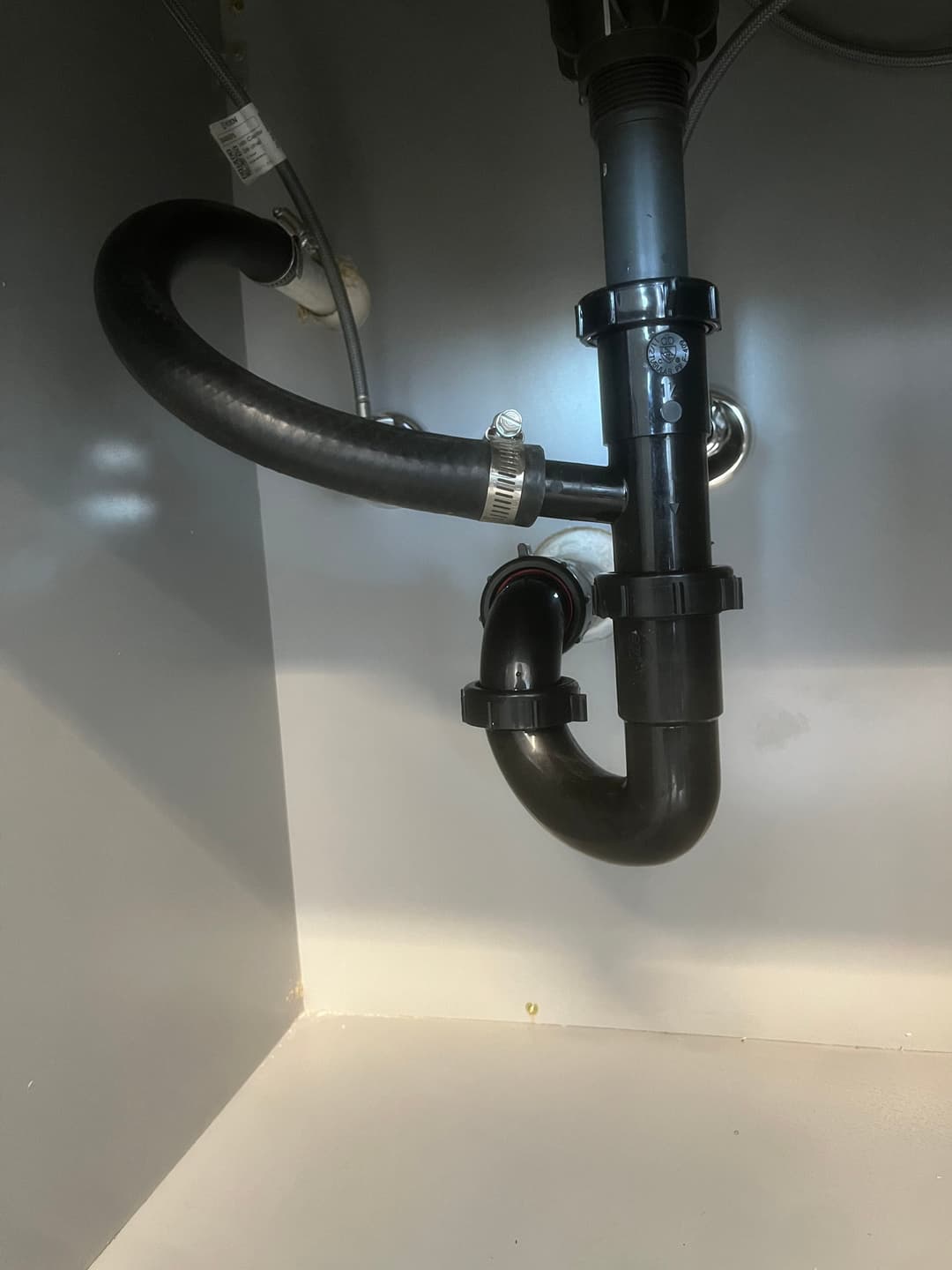 Plumbing pipes and fittings under a sink, showing connections and drainage setup.