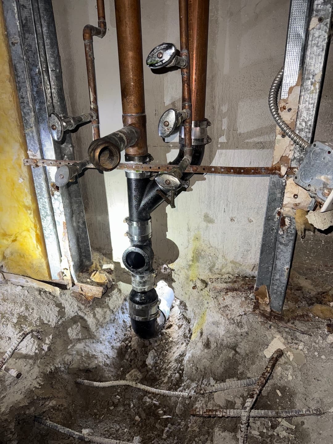 Exposed plumbing pipes and drain pipe installation in a construction site.