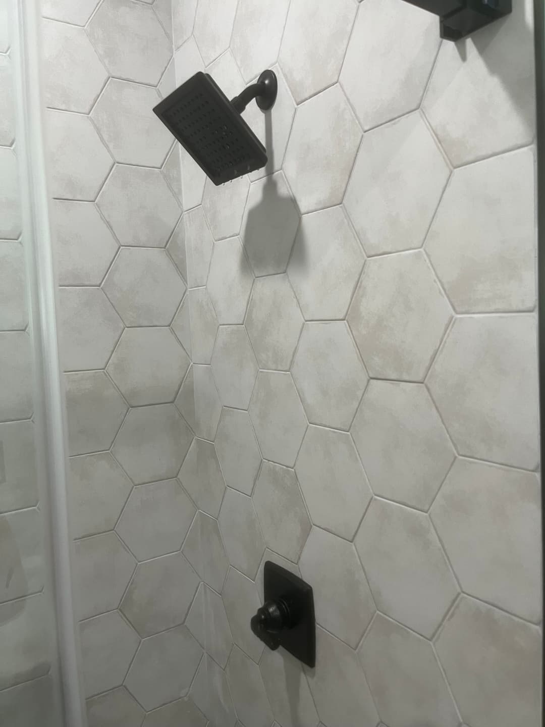 Modern shower with black fixtures and hexagon tile design. Clean, contemporary bathroom aesthetic.