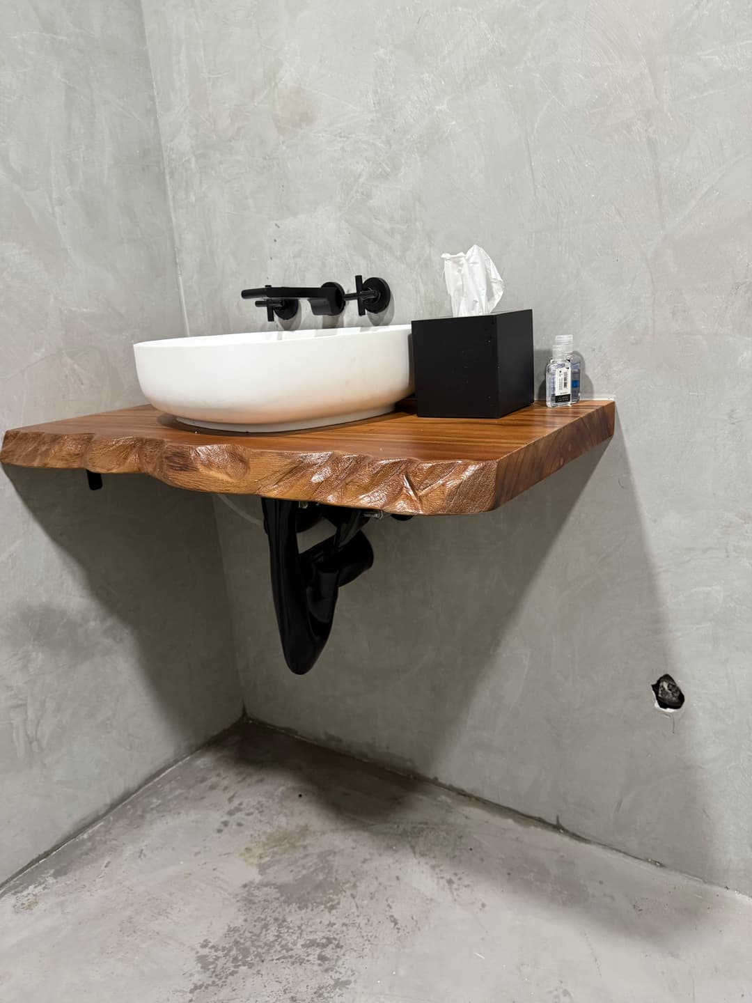 Modern bathroom with a wooden sink and minimalist decor against a textured gray wall.