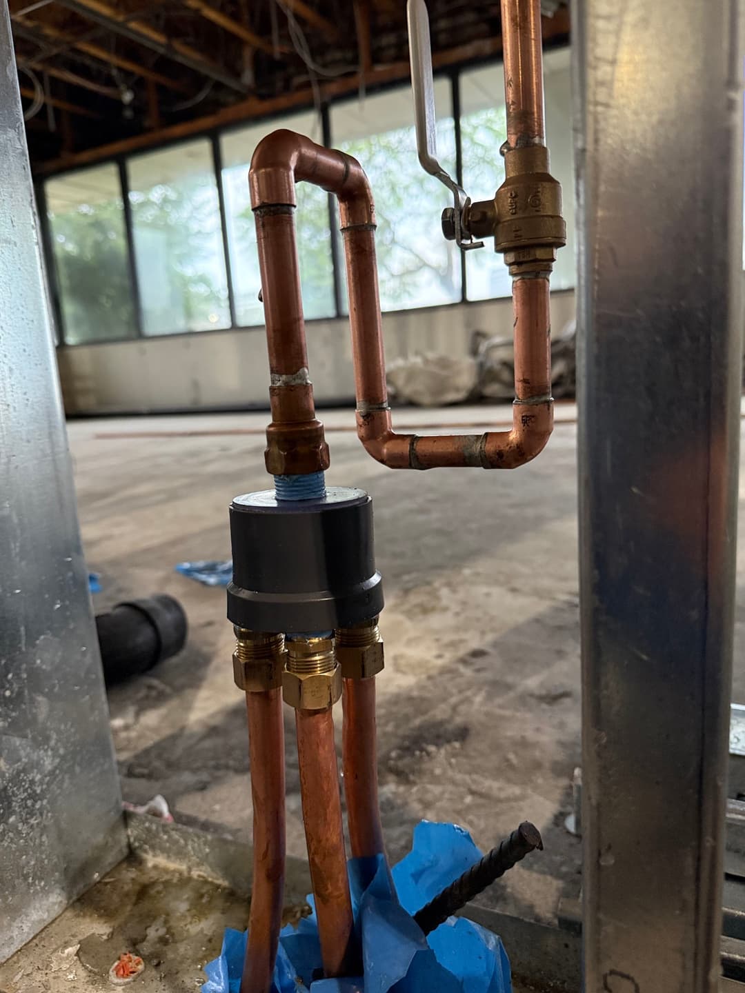Copper plumbing installation with valves and fittings in a construction area.