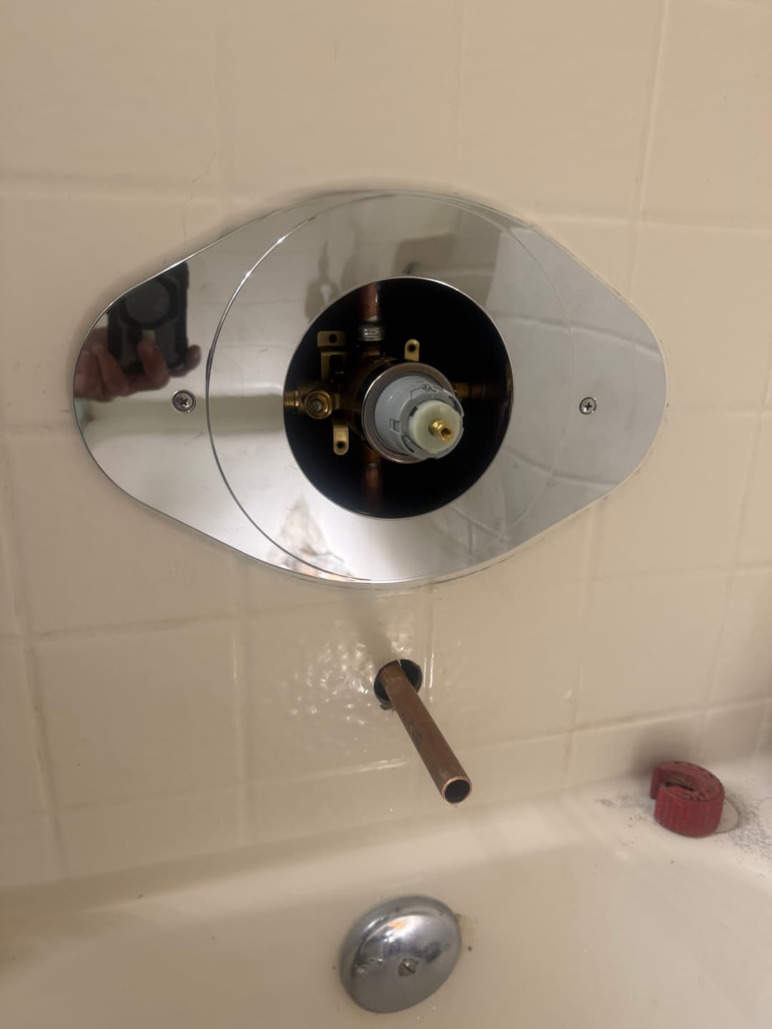 Shower valve assembly installation with chrome plate and exposed copper pipe.