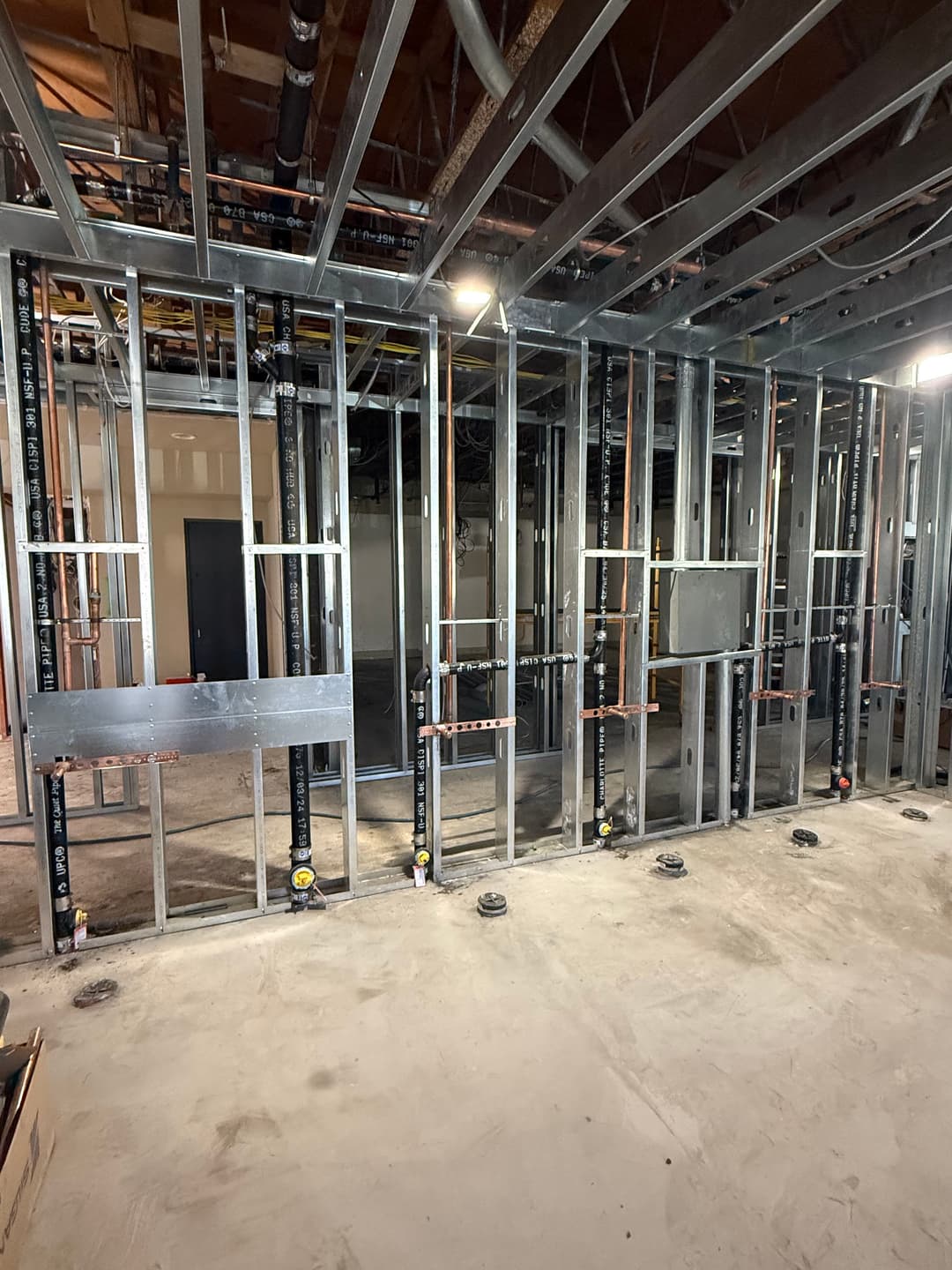 Framed interior construction with metal studs and plumbing pipes in a new building project.