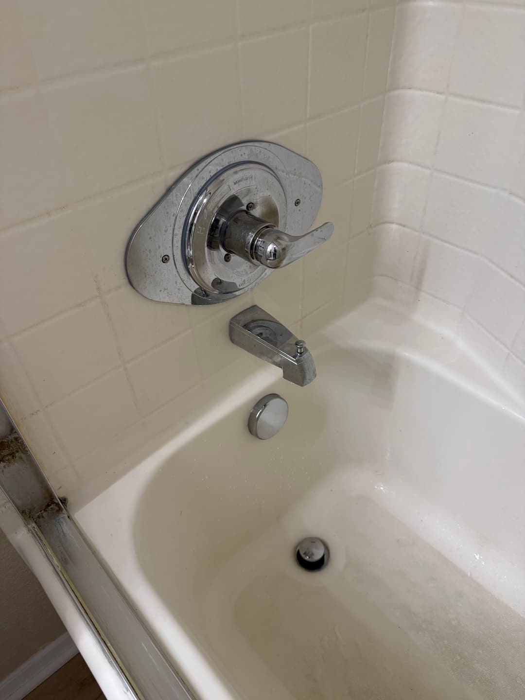 Chrome bathtub faucet and nozzle with tile wall in the background. Clean bathtub area.