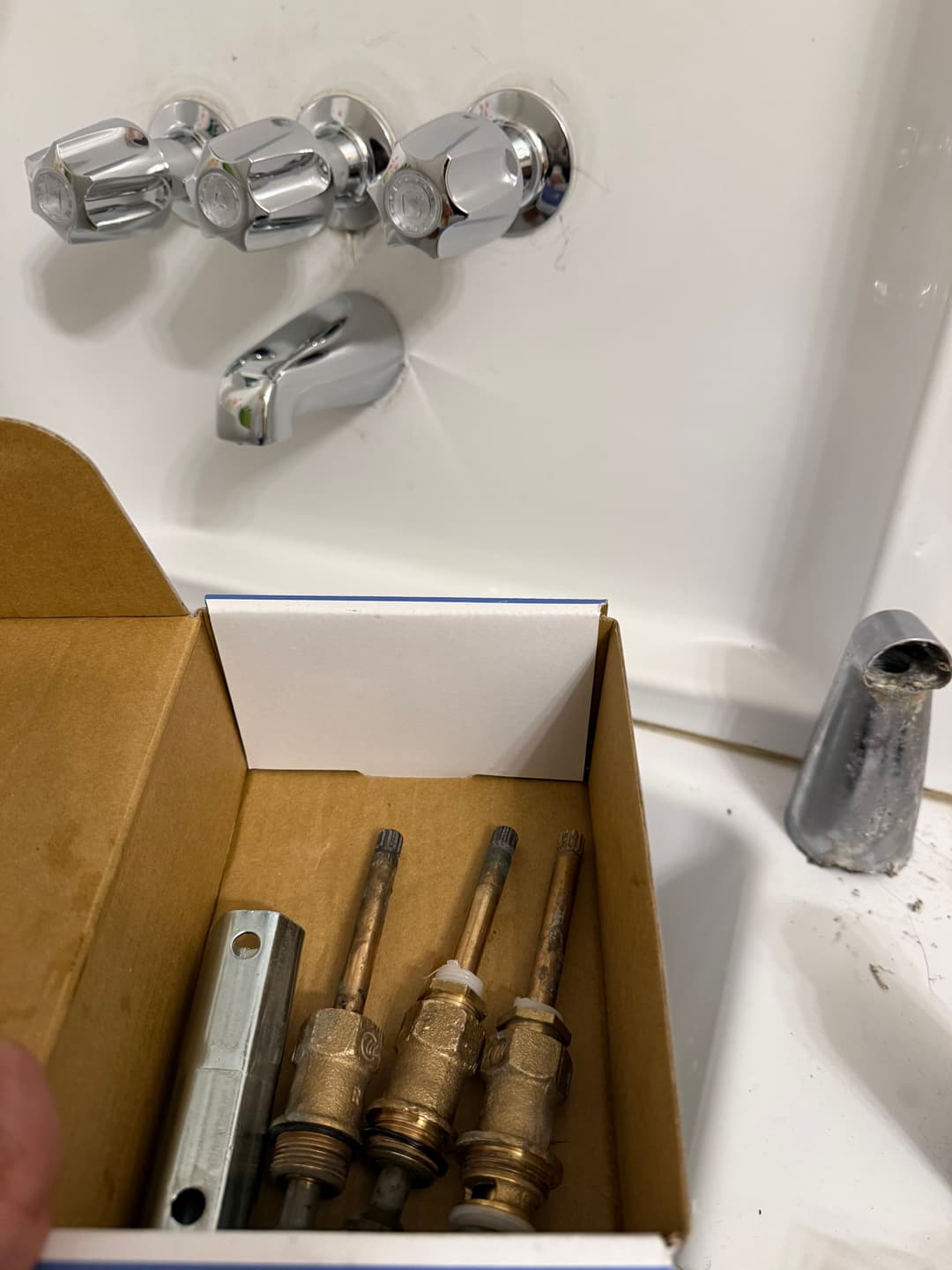 Bathroom faucet components in a box with faucet handles and valves.