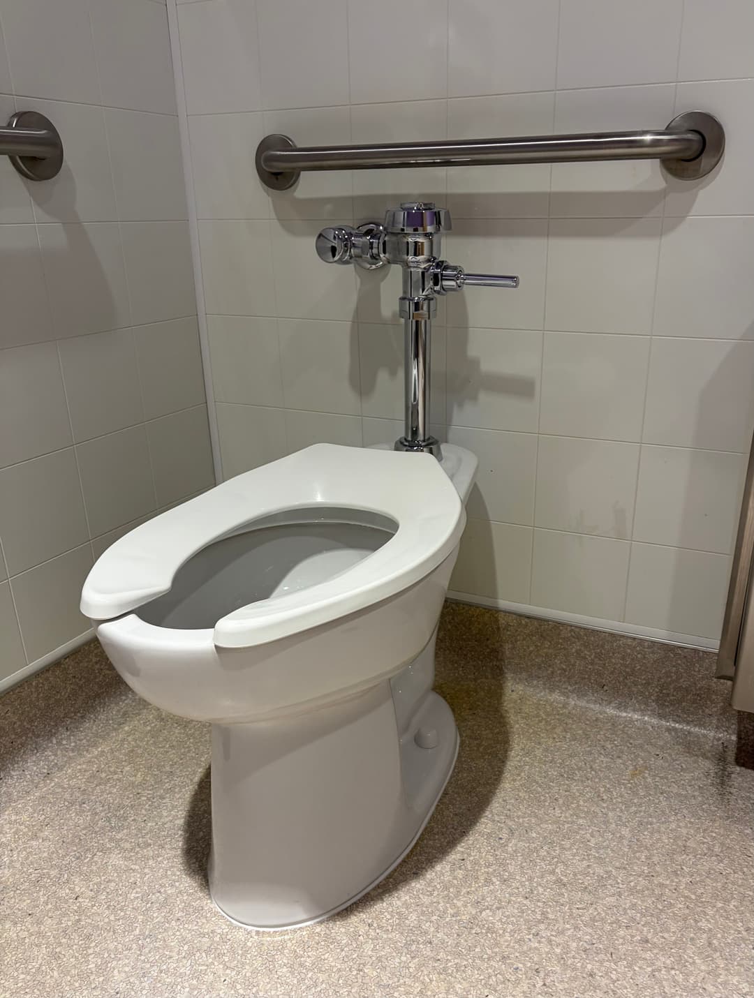 Modern toilet in a restroom with grab bars, designed for accessibility and comfort.