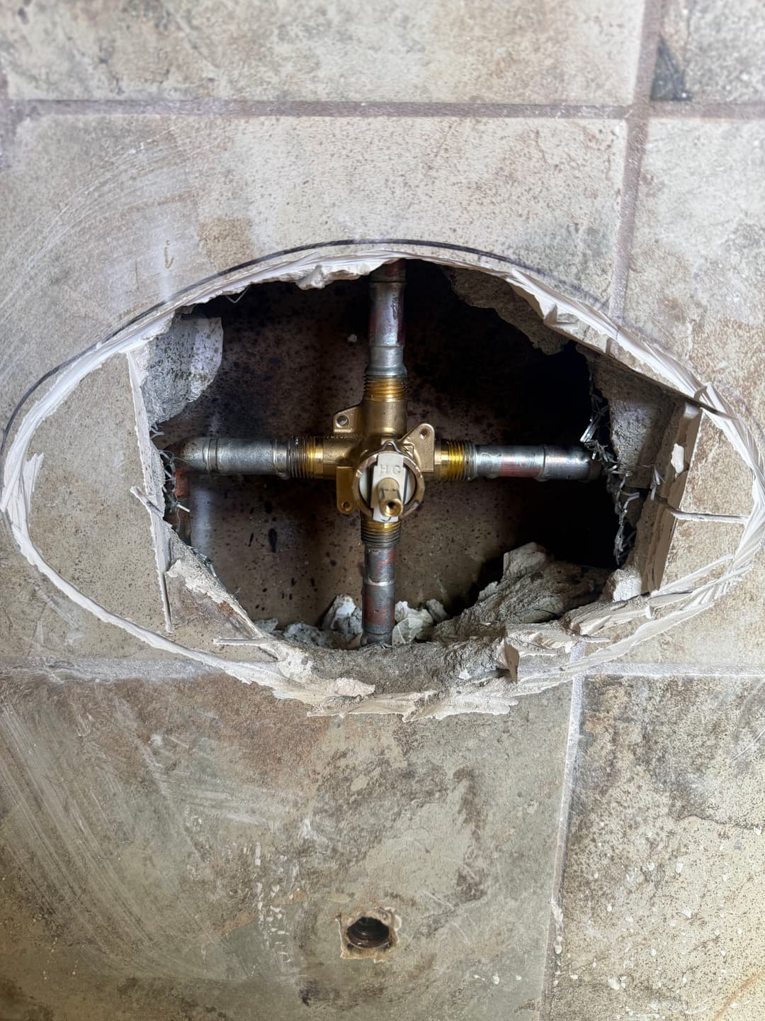 Exposed plumbing repair with cut-out section revealing valves and pipes in a wall.