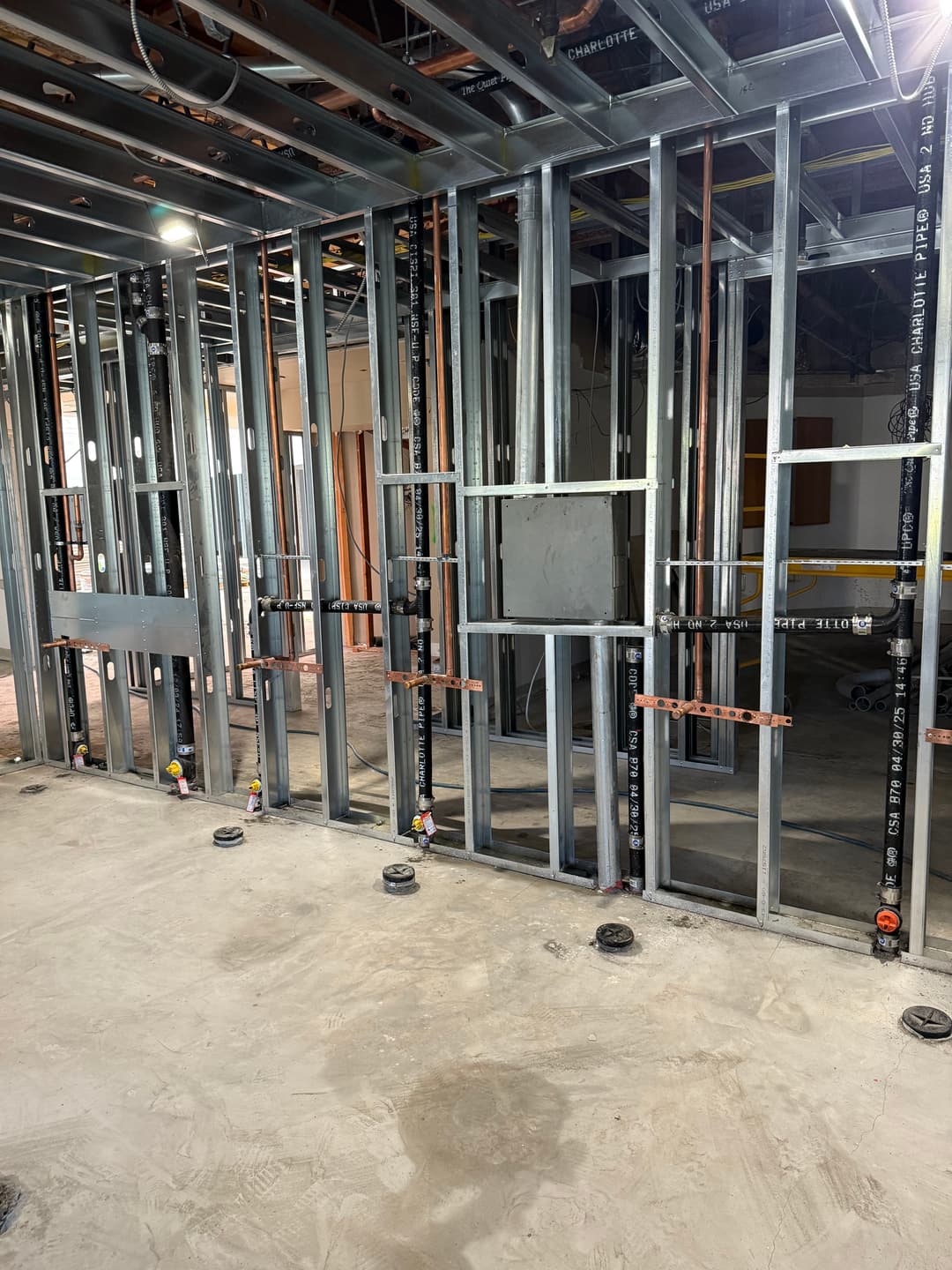 Metal framing in a construction site, showcasing wall structure and electrical wiring setup.