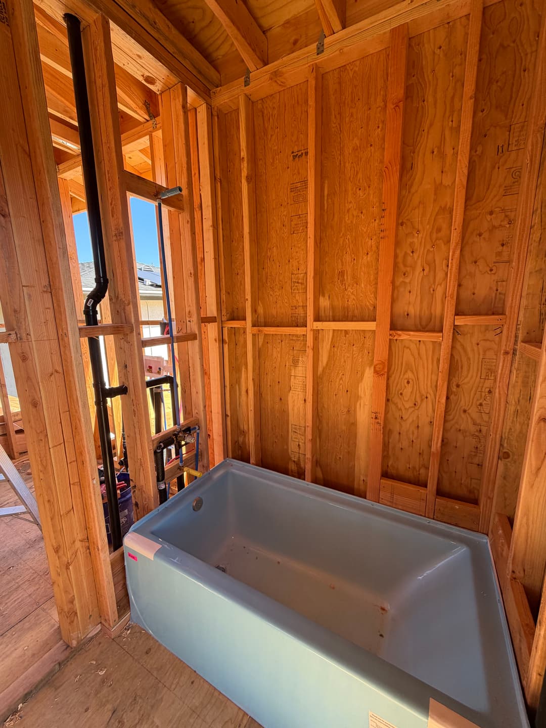 Newly framed bathroom under construction featuring a bathtub installed in wooden walls.