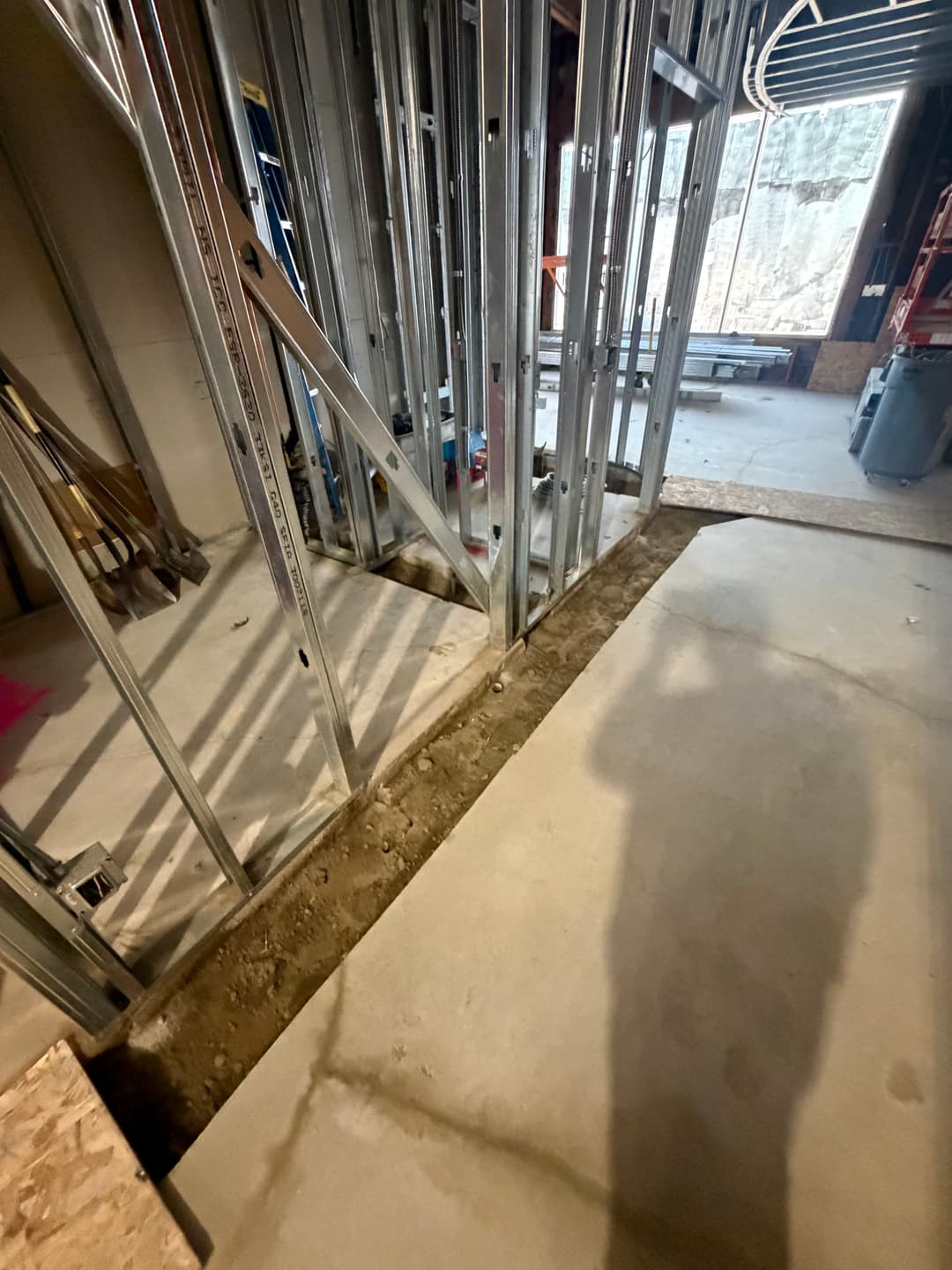 Framed interior wall structure in a basement renovation with unfinished floor concrete.