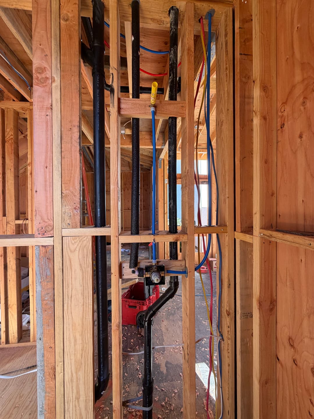 Plumbing installation during home construction showing pipes and framing in progress.