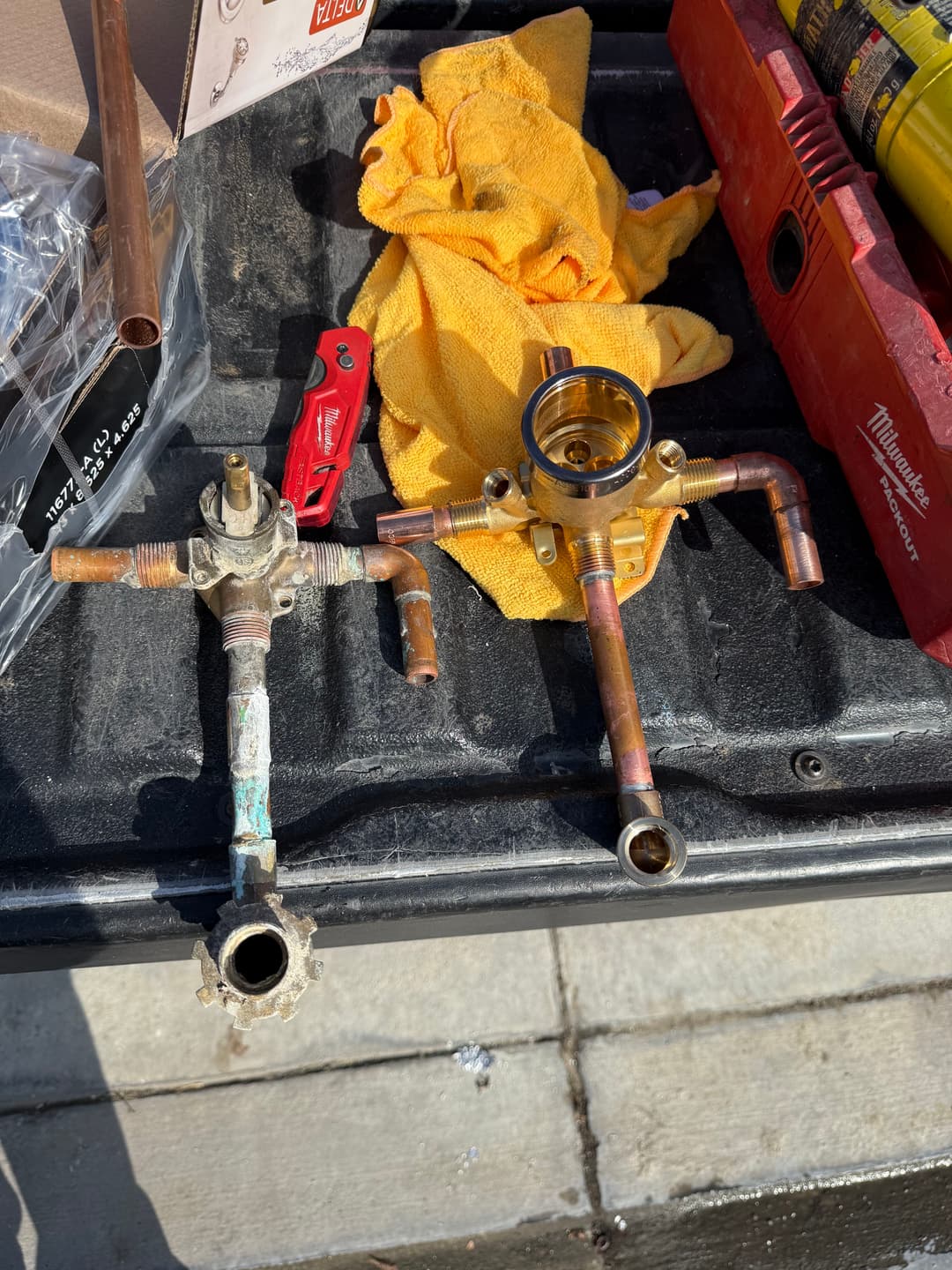 Copper plumbing valves and fittings on a work surface with tools and a yellow cloth.