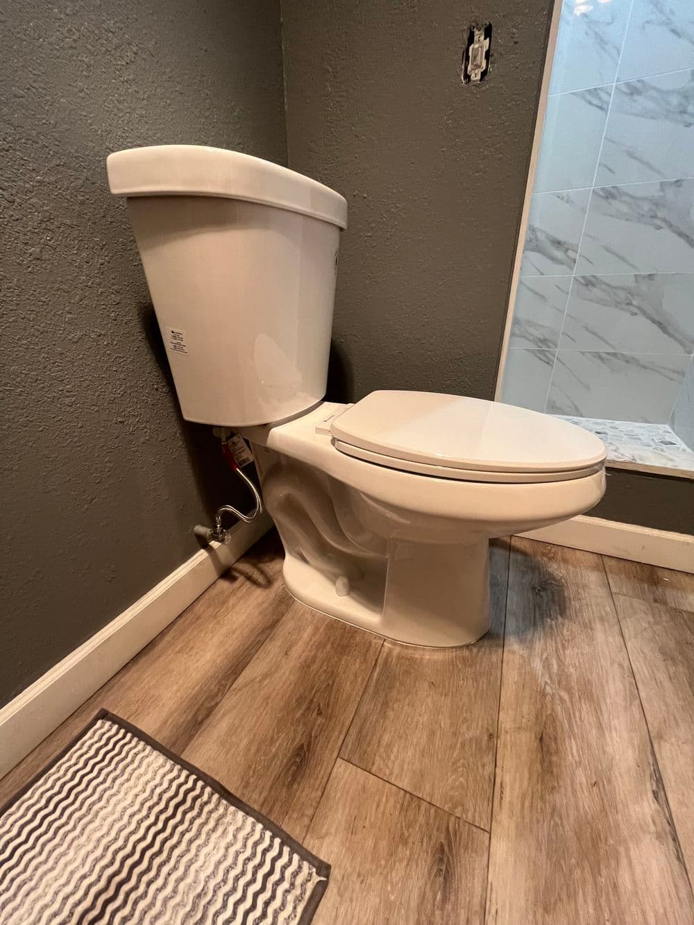 modern white toilet in a bathroom with gray walls and wooden flooring